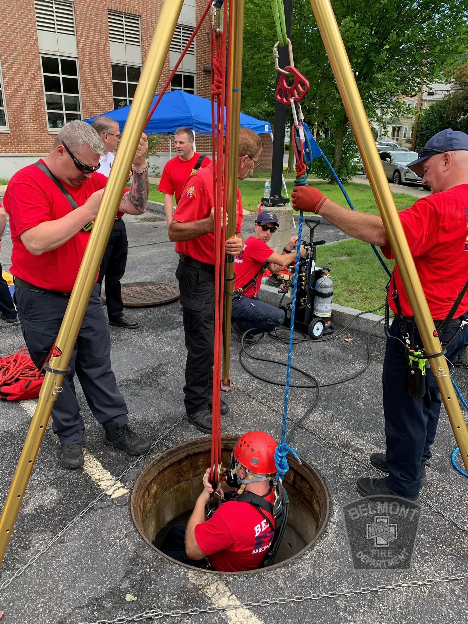 Group of Firefighters Lowering One of Their Own Into a Manhole
